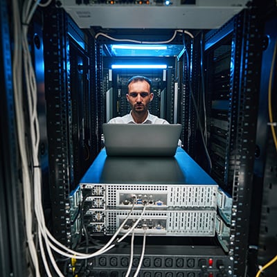 A cybersecurity professional working on a laptop resting on computer switchers