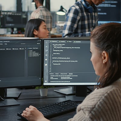 A woman sits in front of computer screens checking security protocols