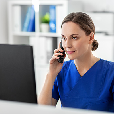 A medical professional behind a computer on the phone